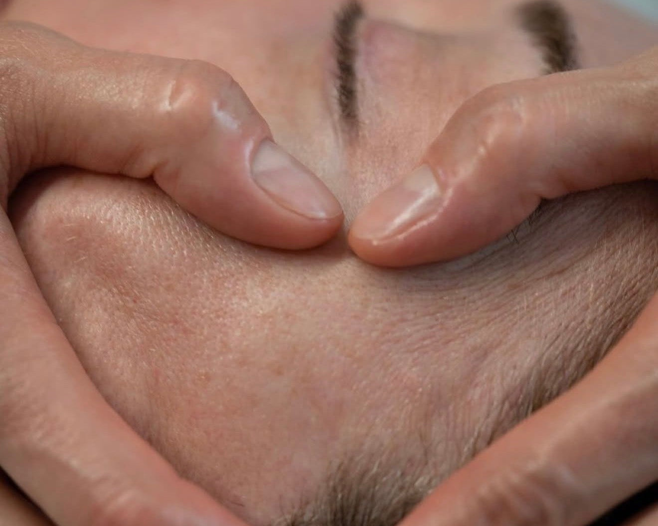 Close-up shot of an aesthetician performing a sculptural facial massage on a client's forehead to relieve tension, highlighting the technical and therapeutic skin rituals at Luxe & Luna boutique spa.