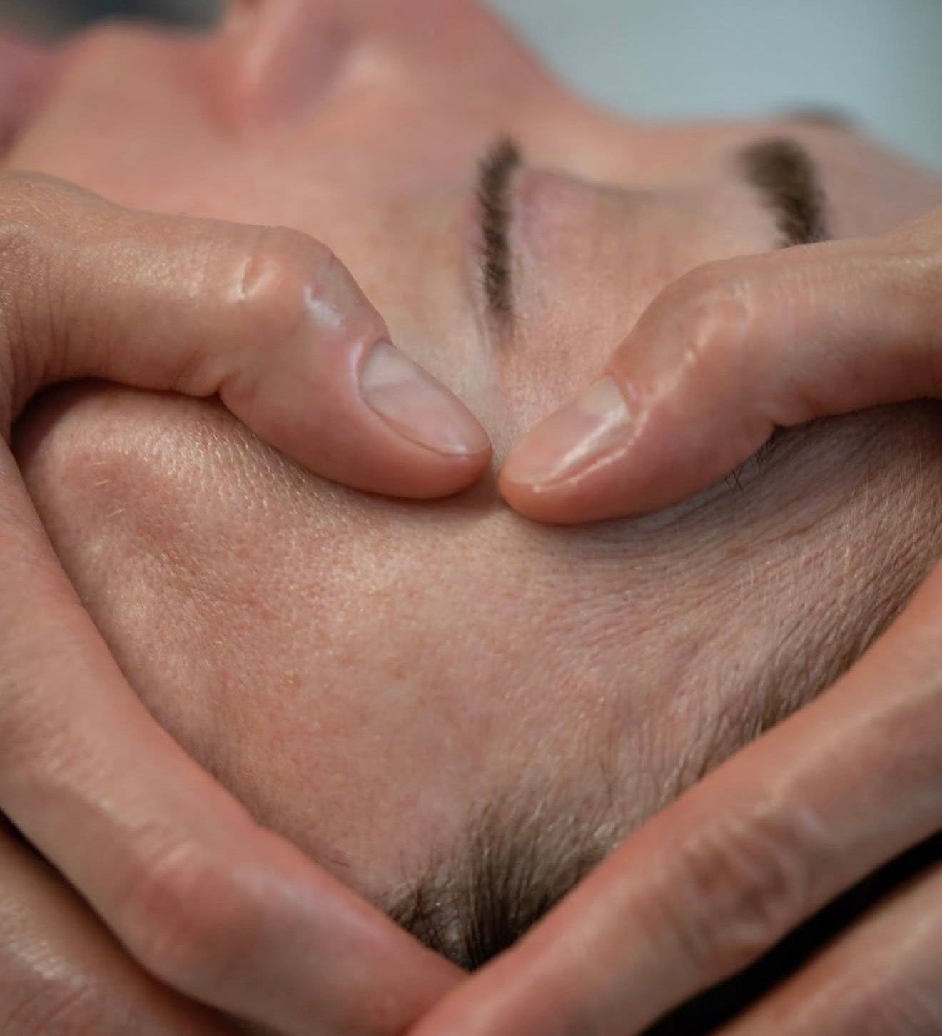 Close-up shot of an aesthetician performing a sculptural facial massage on a client's forehead to relieve tension, highlighting the technical and therapeutic skin rituals at Luxe & Luna boutique spa.
