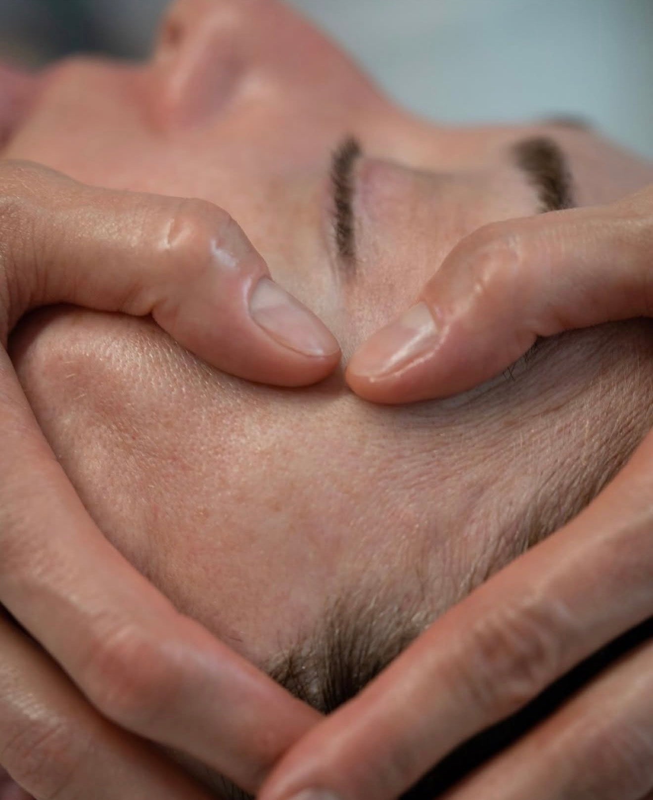 Close-up shot of an aesthetician performing a sculptural facial massage on a client's forehead to relieve tension, highlighting the technical and therapeutic skin rituals at Luxe & Luna boutique spa.